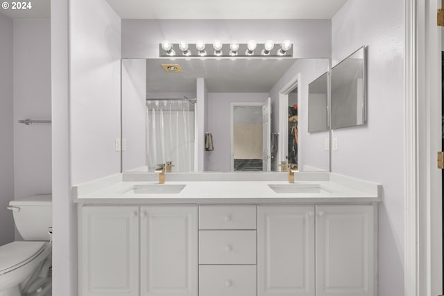 bathroom featuring dual bowl vanity and toilet