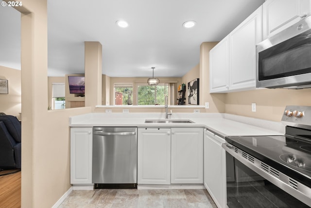 kitchen with kitchen peninsula, stainless steel appliances, sink, light wood-type flooring, and white cabinets