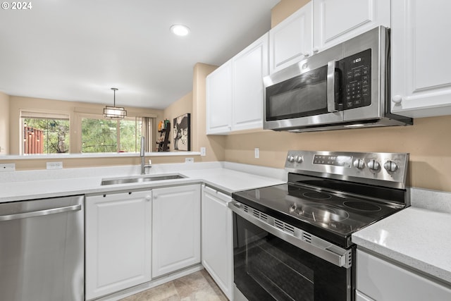 kitchen featuring hanging light fixtures, light tile patterned floors, stainless steel appliances, white cabinetry, and sink