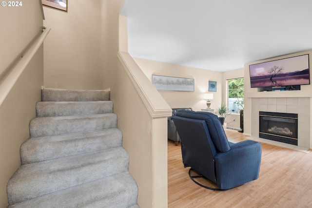 stairs with hardwood / wood-style floors and a tile fireplace