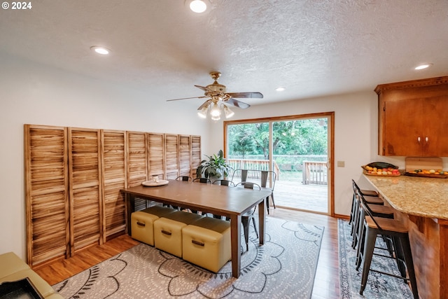 dining room with ceiling fan, a textured ceiling, and light hardwood / wood-style flooring