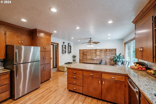 42681 Island Inn Dr, Lebanon, OR 97355 - kitchen featuring appliances with stainless steel finishes, light wood finished floors, a textured ceiling, a ceiling fan, and brown cabinetry