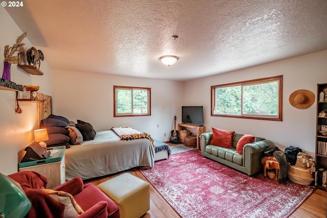 bedroom featuring hardwood / wood-style floors, a textured ceiling, and multiple windows