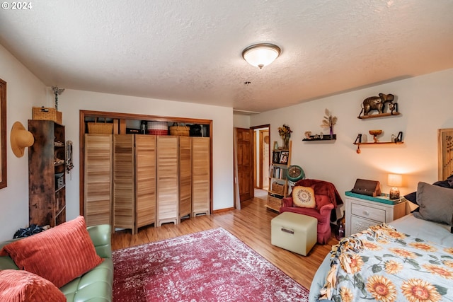 bedroom with a textured ceiling, light hardwood / wood-style flooring, and a closet