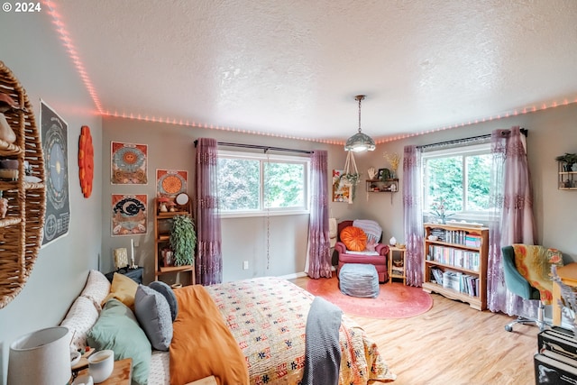 bedroom featuring wood-type flooring, a textured ceiling, and multiple windows