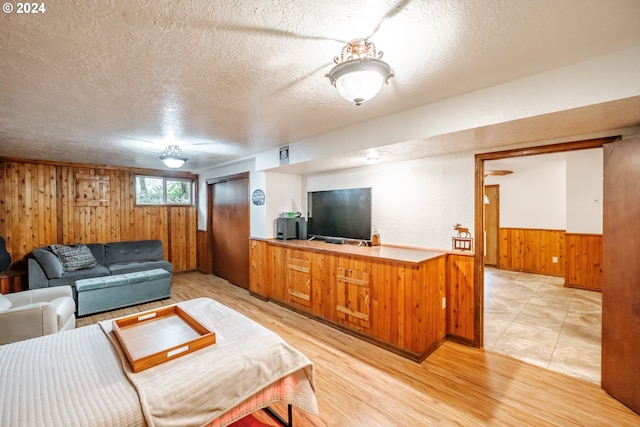 living room with hardwood / wood-style flooring, a textured ceiling, and wooden walls