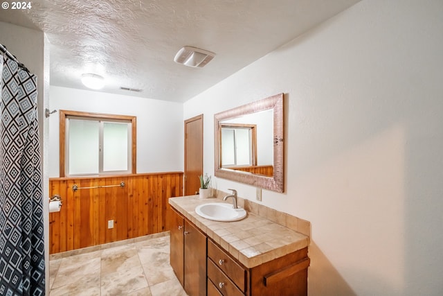 42681 Island Inn Dr, Lebanon, OR 97355 - bathroom with wooden walls, vanity, a textured ceiling, and wainscoting