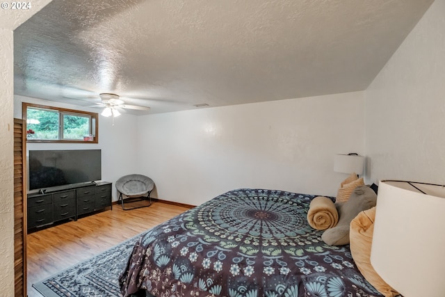 bedroom with a textured ceiling, hardwood / wood-style flooring, and ceiling fan