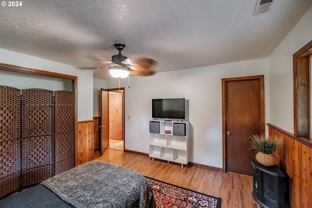 42681 Island Inn Dr, Lebanon, OR 97355 - bedroom with wood finished floors, wood walls, a textured ceiling, ceiling fan, and wainscoting
