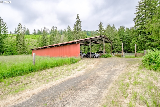 42681 Island Inn Dr, Lebanon, OR 97355 - view of outdoor structure featuring driveway, a view of trees, and a detached carport