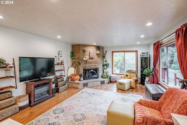 living room with a stone fireplace and light hardwood / wood-style flooring