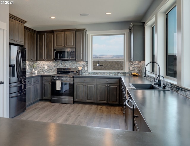 kitchen with appliances with stainless steel finishes, dark countertops, a sink, and tasteful backsplash