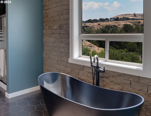 full bath featuring a soaking tub, a sink, baseboards, and tile patterned floors