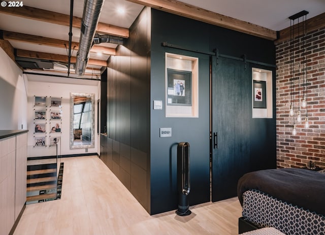 interior space featuring a barn door, brick wall, and light hardwood / wood-style flooring