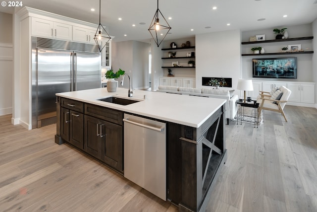 kitchen featuring light wood-type flooring, sink, a kitchen island with sink, white cabinetry, and appliances with stainless steel finishes