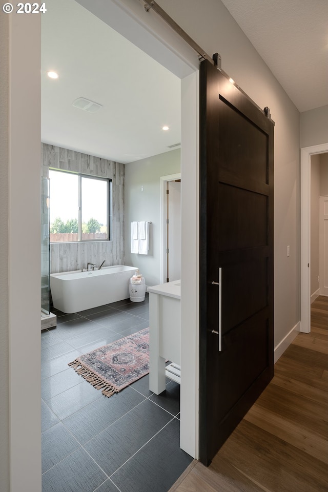 corridor featuring a barn door and dark hardwood / wood-style flooring