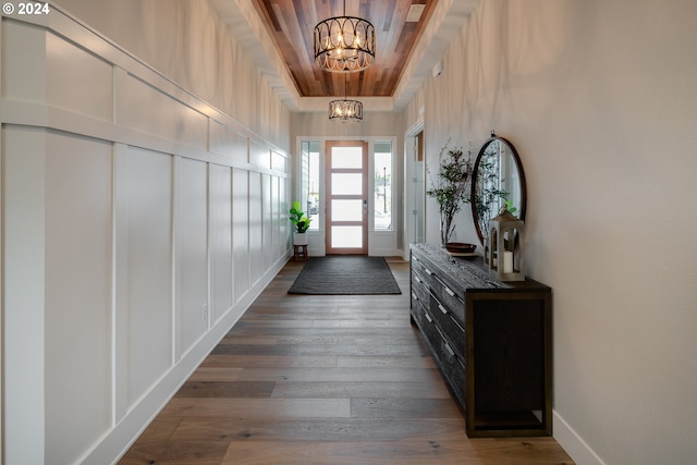 entryway featuring a notable chandelier, wood-type flooring, a raised ceiling, and wood ceiling