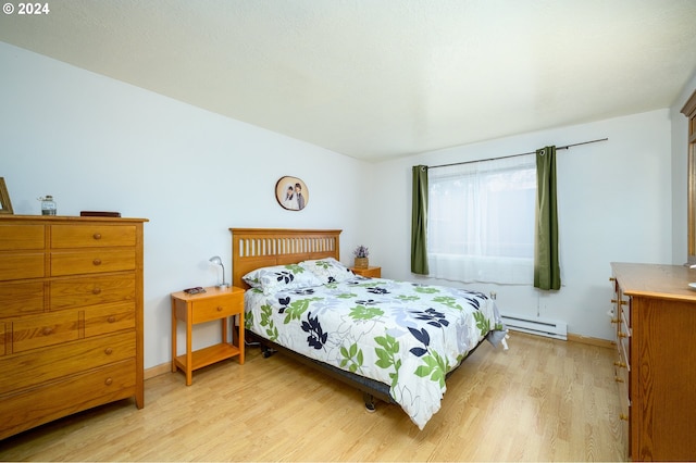 bedroom with a baseboard radiator, light wood-type flooring, and baseboards