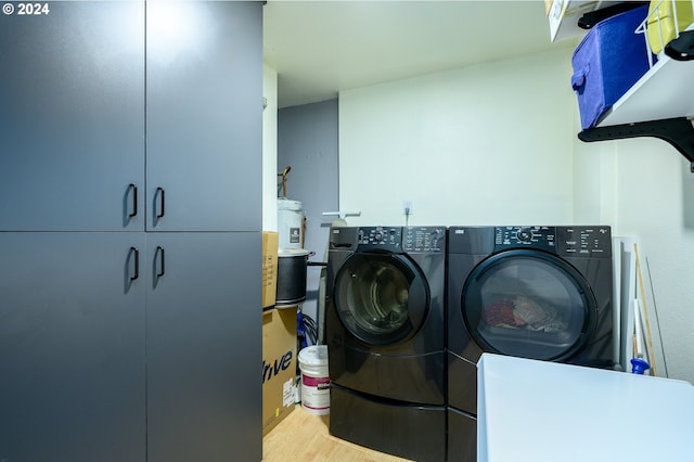 laundry room featuring light hardwood / wood-style floors, washing machine and dryer, cabinets, and water heater