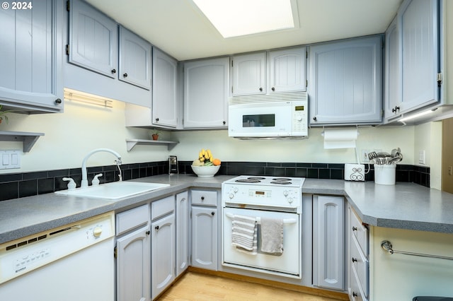 kitchen with white appliances, sink, light wood-type flooring, and gray cabinets