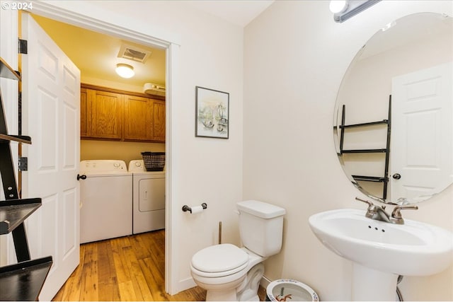 bathroom with washer and dryer, toilet, wood-type flooring, and sink