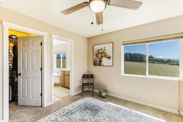 bedroom with light carpet, a closet, ensuite bathroom, and ceiling fan