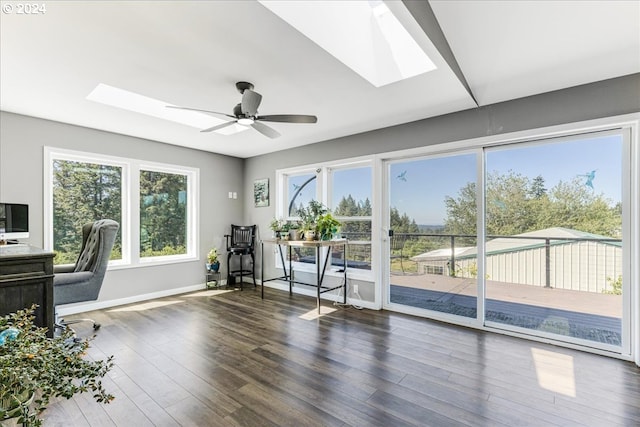 exercise area with a skylight, ceiling fan, and dark wood-type flooring