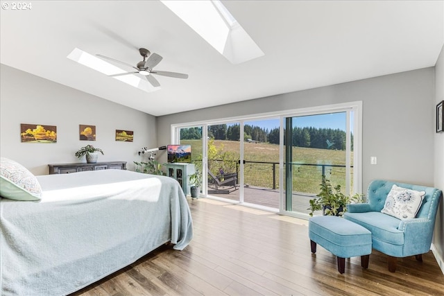 bedroom with hardwood / wood-style floors, access to outside, lofted ceiling with skylight, and ceiling fan