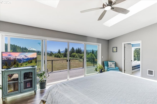 bedroom with access to exterior, ceiling fan, dark wood-type flooring, and vaulted ceiling with skylight