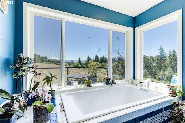 interior space with a relaxing tiled tub and a healthy amount of sunlight