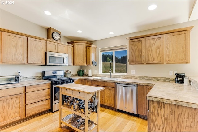 kitchen with light brown cabinets, stainless steel appliances, light hardwood / wood-style floors, and sink