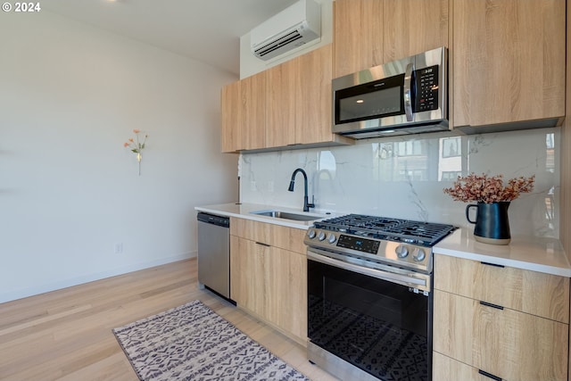 kitchen featuring a wall mounted AC, light hardwood / wood-style flooring, stainless steel appliances, light brown cabinetry, and sink