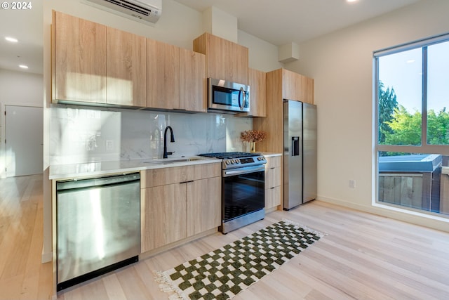 kitchen with sink, light brown cabinets, light hardwood / wood-style floors, tasteful backsplash, and appliances with stainless steel finishes