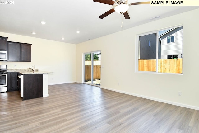 unfurnished living room featuring ceiling fan, sink, and light wood-type flooring