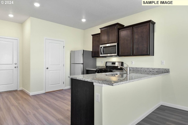 3907 SW Duniway Ln, Gresham, OR 97080 - kitchen featuring appliances with stainless steel finishes, wood finished floors, dark brown cabinets, baseboards, and a peninsula