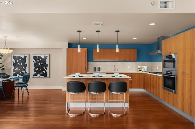 kitchen with tasteful backsplash, a kitchen island, hanging light fixtures, wall chimney exhaust hood, and wood-type flooring