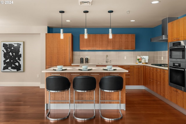 kitchen with wall chimney exhaust hood, dark wood-type flooring, a kitchen island, and backsplash