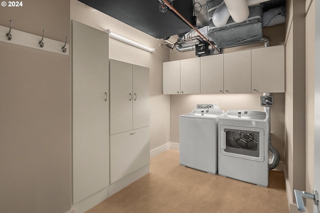 laundry room featuring light tile patterned floors, separate washer and dryer, and cabinets