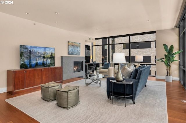 living room with a fireplace, expansive windows, and light hardwood / wood-style floors