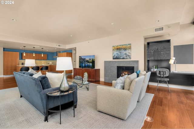 living room featuring light hardwood / wood-style floors and a tiled fireplace