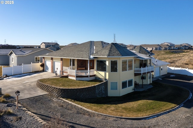 view of front of property featuring a garage, concrete driveway, a residential view, fence, and a front lawn