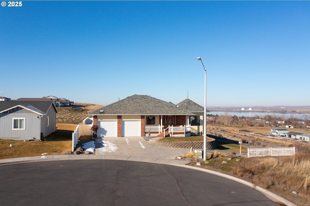 view of front of property featuring covered porch, a garage, a water view, fence, and concrete driveway