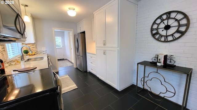 1400 W 40th St, Eugene, OR 97405 - kitchen with stainless steel appliances, white cabinetry, dark tile patterned floors, a sink, and backsplash