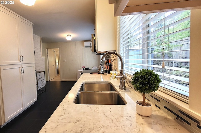 1400 W 40th St, Eugene, OR 97405 - kitchen featuring a sink, white cabinetry, light stone counters, and wooden walls