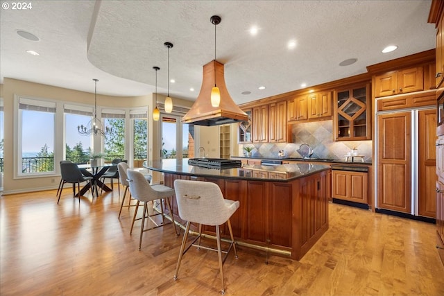 kitchen featuring hanging light fixtures, a textured ceiling, light hardwood / wood-style floors, and a spacious island