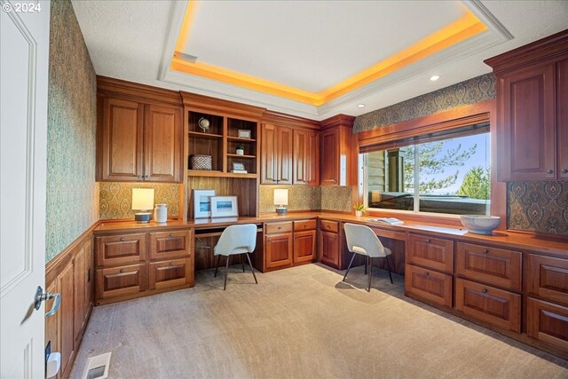 office featuring light colored carpet, built in desk, and a raised ceiling