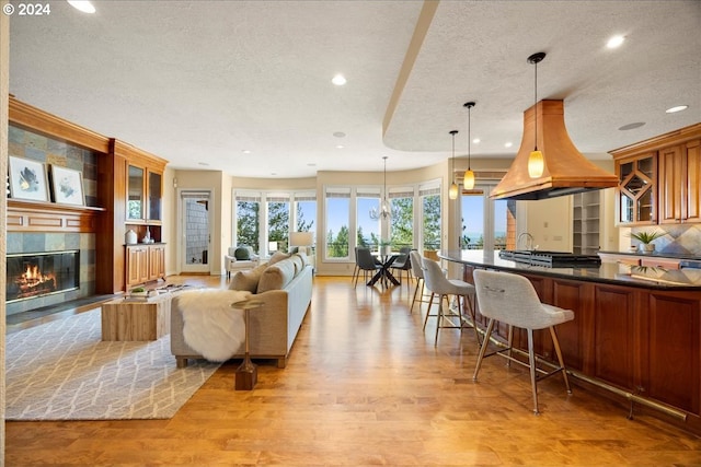 living room featuring a tiled fireplace, a textured ceiling, and light hardwood / wood-style flooring