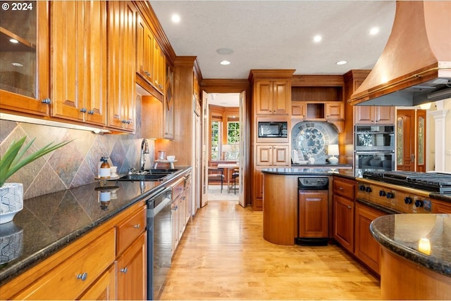 kitchen featuring appliances with stainless steel finishes, custom range hood, decorative backsplash, sink, and light hardwood / wood-style floors