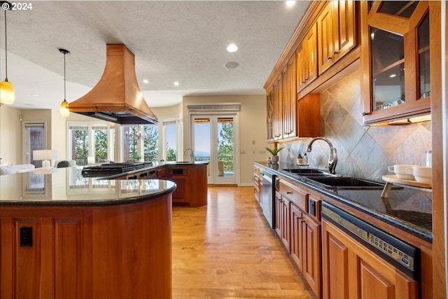 kitchen with light hardwood / wood-style floors, custom range hood, decorative light fixtures, a wealth of natural light, and a center island