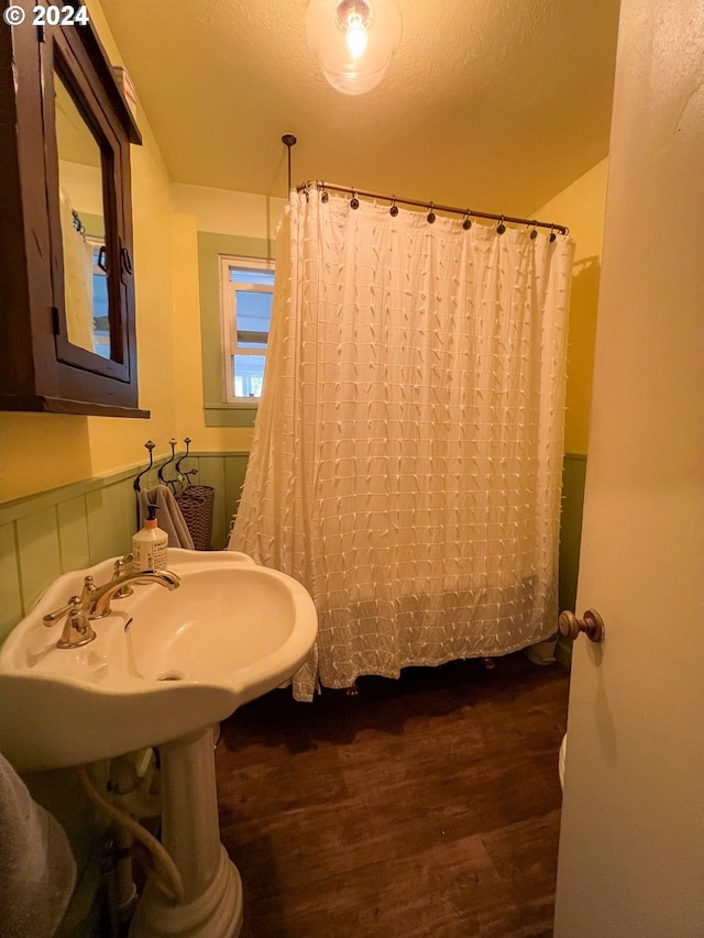 bathroom featuring a wainscoted wall, a textured ceiling, a shower with shower curtain, and wood finished floors